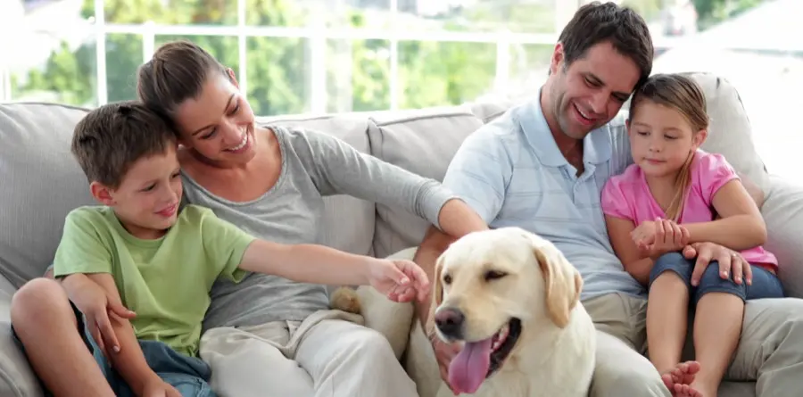 Family relaxing at home on a couch with their dog