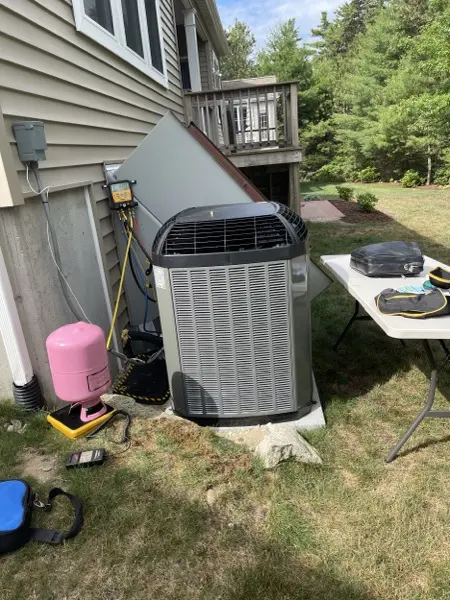 Outdoor condenser unit being installed beside a home