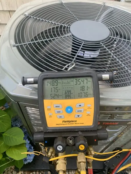Technician reading refrigerant gauges on an outdoor unit