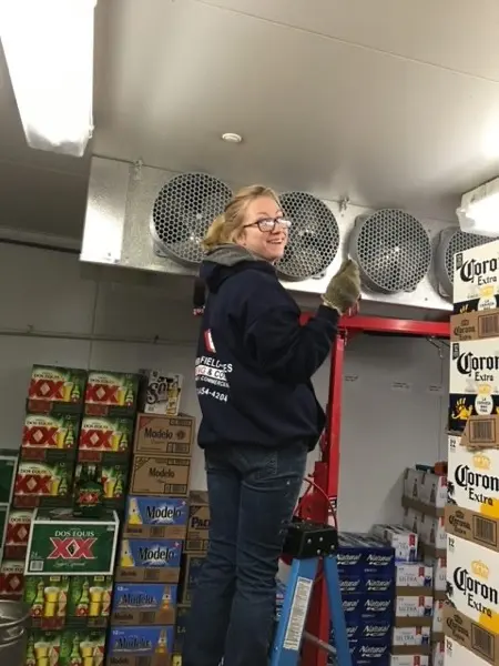 Technician servicing refrigeration equipment in a commercial walk-in cooler